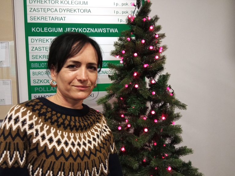 Kobieta stoi obok świątecznej choinki