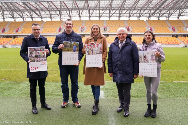 Pięć osób stoi na murawie boiska.