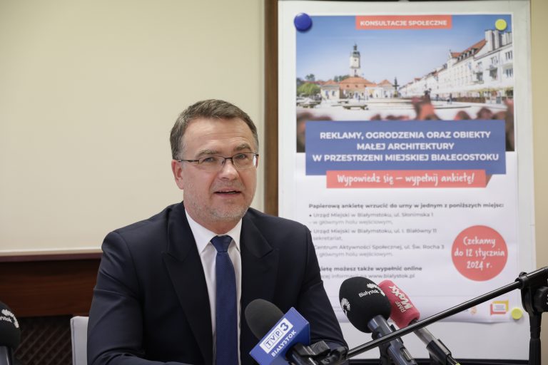 Mężczyzna siedzi przed mikrofonami.