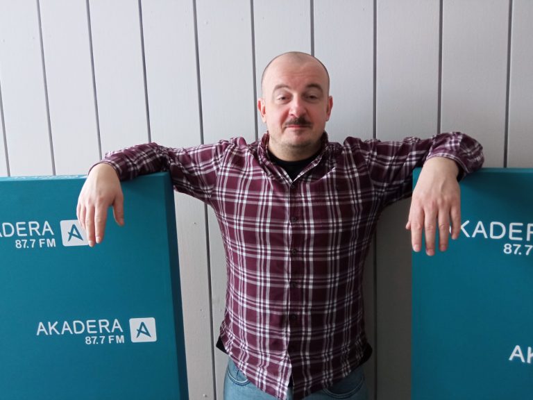 Mężczyna stoi z opartymi ramionami na logo radia