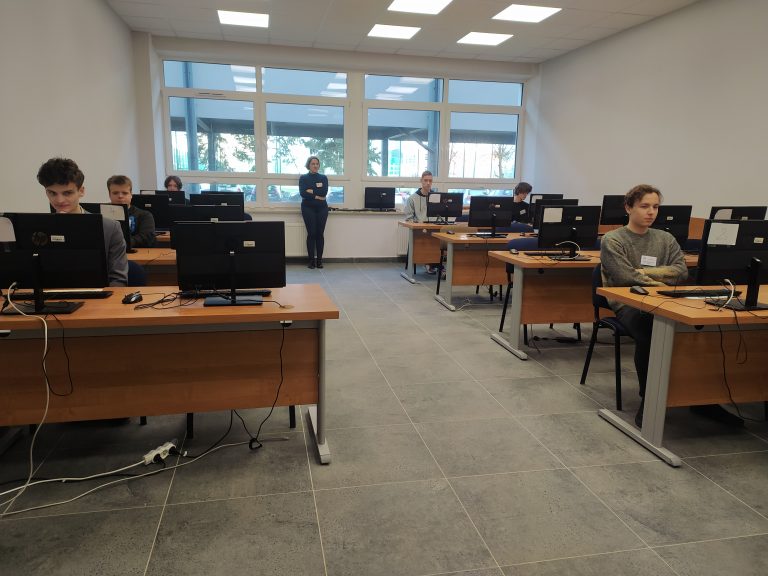 Uczniowie siedzą przed komputerami.