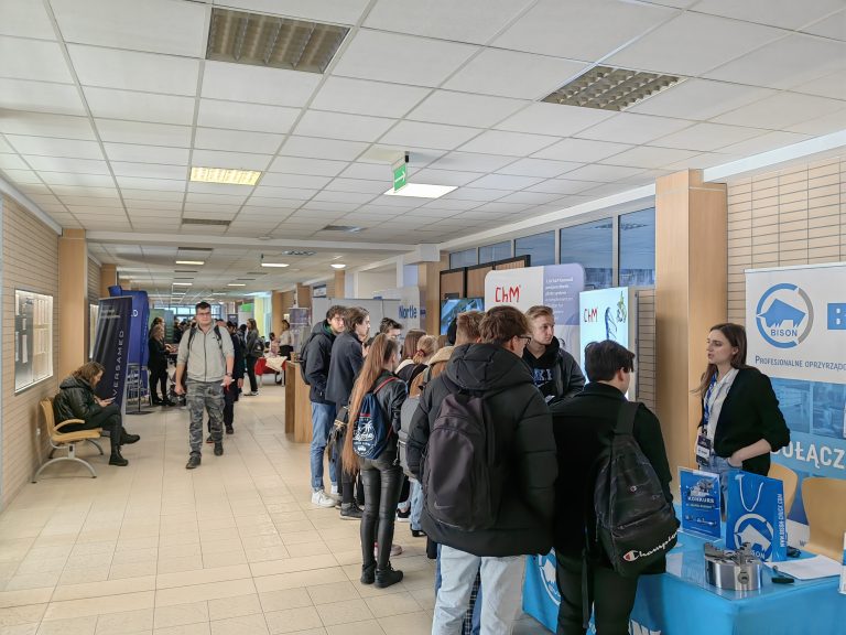 Studenci stoją przy stoiskach.
