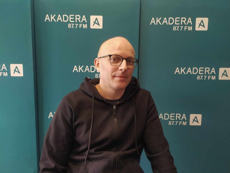 Mężczyzna na firmowej ściance promocyjnej.