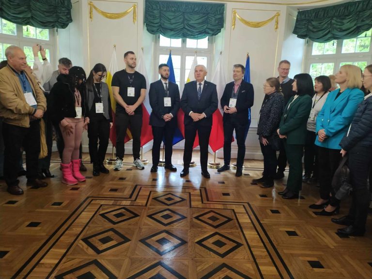 Międzynarodowe spotkanie ludzi w uroczystej sali.