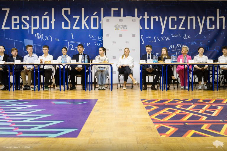 Uczniowie siedzą na apelu.