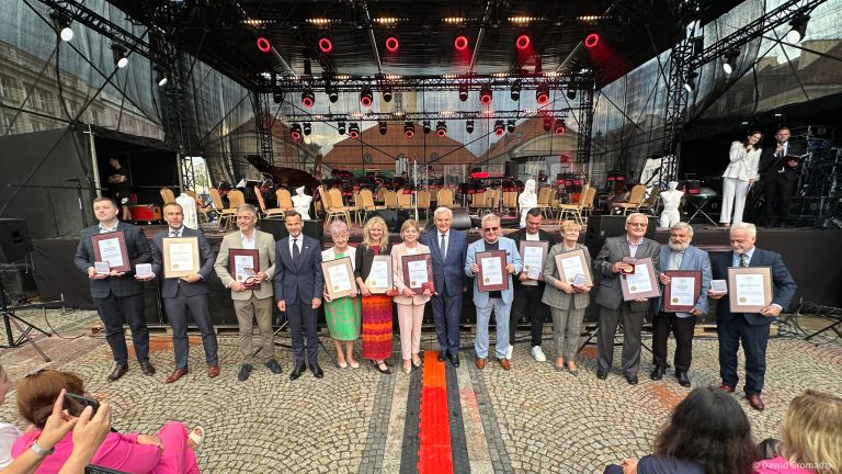 Ludzie przed sceną pozują do zdjęcia,.