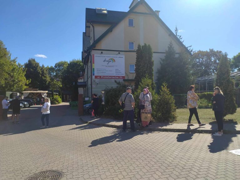 Ludzie czekają w kolejce przed budynkiem.