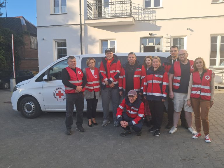Wolontariusze stoją przy samochodzie.