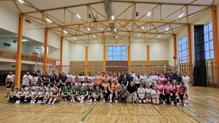 Siatkarki pozują na hali sportowej.