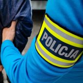 Ręka policja trzyma mężczyznę w kajdankach.