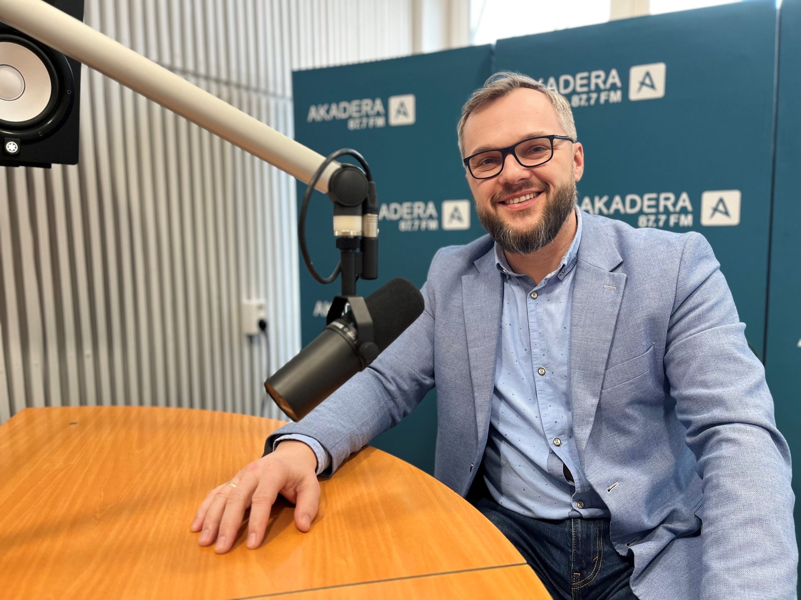uśmiechnięty mężczyzna w średnim wieku, w okularach jasnej marynarce siwy