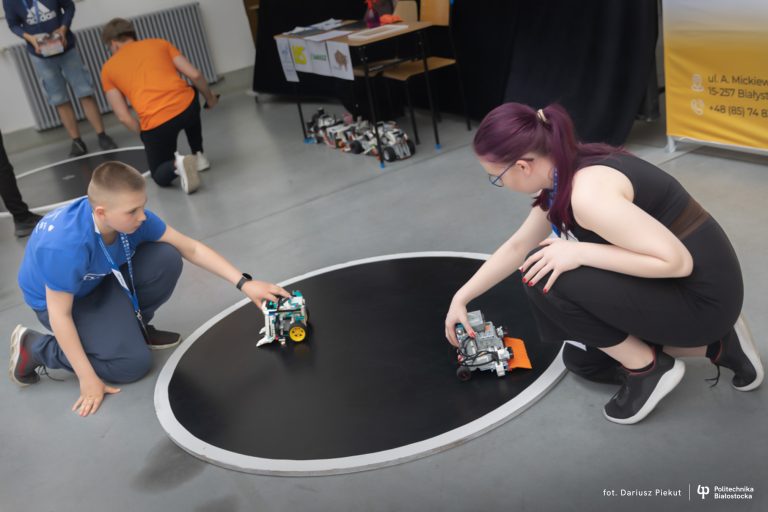 Dwie osoby trzymają roboty na ringu.