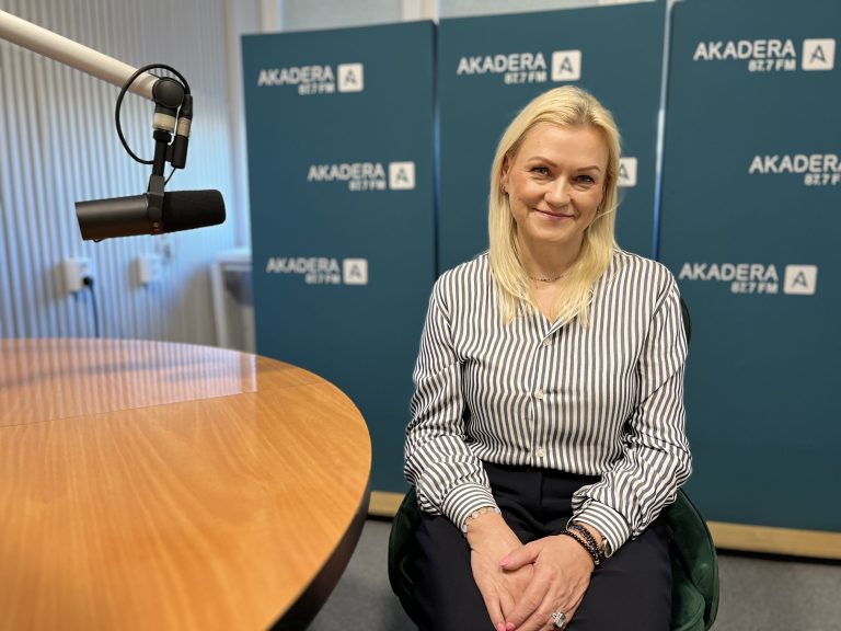 Dr inż. Dorota Dec, blondynka w pasiastym koszuli, siedzi przy stole w studiu Radia Akadera, z mikrofonem po lewej stronie i logotypami stacji w tle.