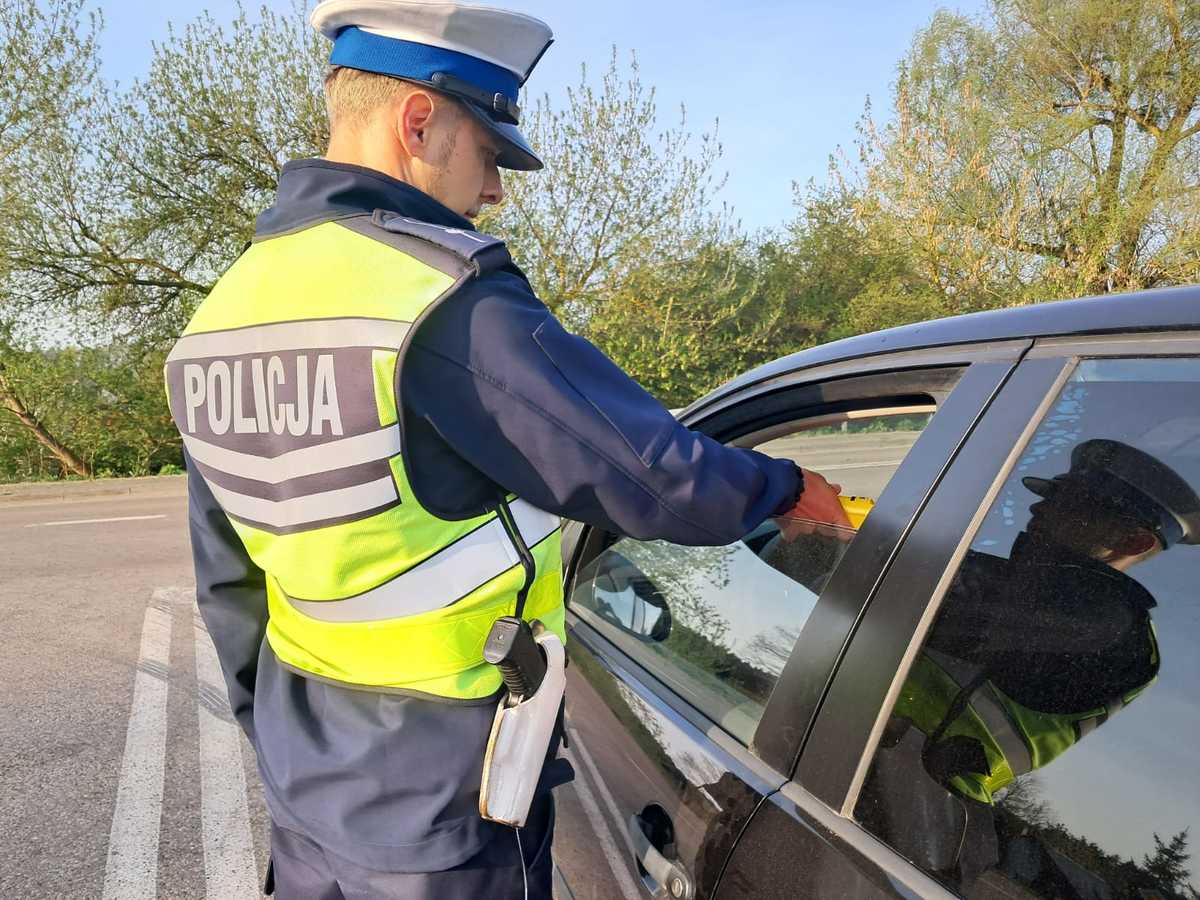 Policjant z alkomatem, kontroluje kierowce