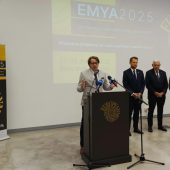 Zdjecie z konferencji zapowiadajcej Kongres Muzealnikow, na srodku stoi 5 osob, mezczyzna przemawia, pozostali stoja obok, w tle logo EMYA