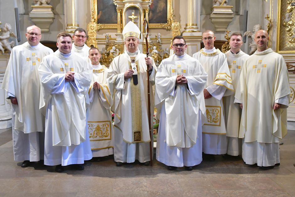 Nowo wyświęceni kapłani wraz z arcybiskupem Józefem Guzdkiem i księżmi uczestniczącymi w uroczystości w Archikatedrze Białostockiej. Grupa duchownych ubranych w białe ornaty stoi na tle ołtarza.