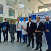 mezczyzni stoja na tle scianki z napisem Uniwersytecki Kliniczny Szpital
