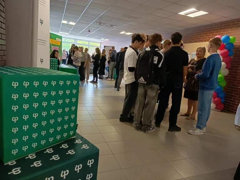 Korytarz uczelni stoja mlodzi ludzi, uczniowie, studenci, nauczyciele wykladowcy, na pierwszym planie widac logotypy Politechniki Bialostockiej, trwa przerwa przed wykladem
