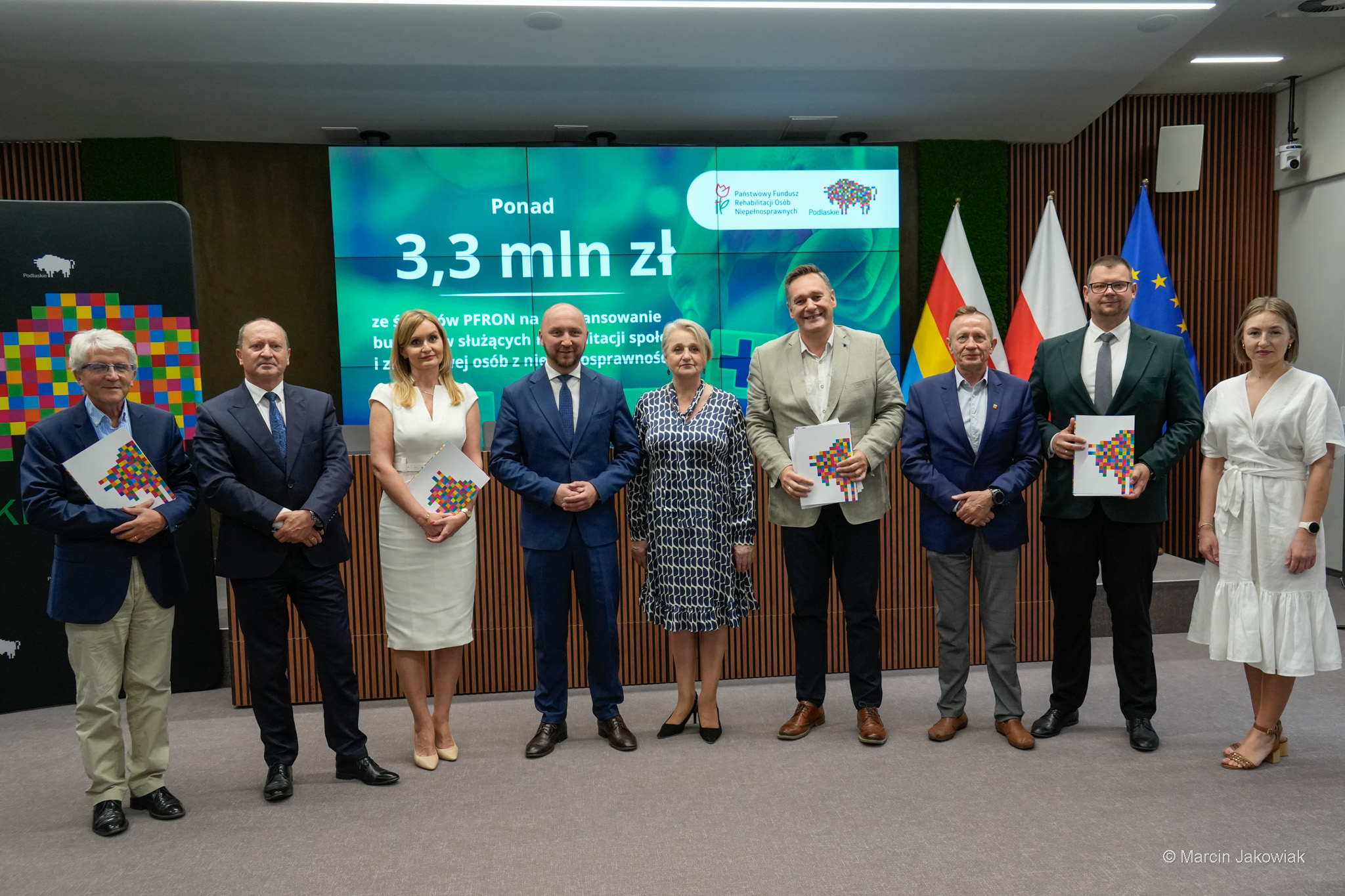 Ludzie pozują do zdjęcia na konferencji.