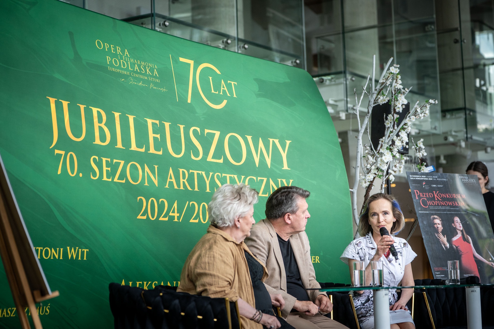 Trzy osoby siedzą na konferencji.