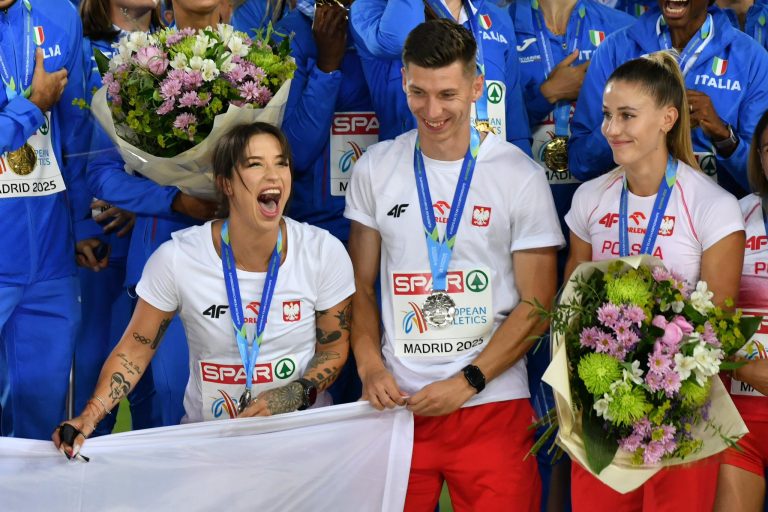 Sportowcy trzymają flagę.