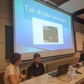 Uczniowie prezentują grę na telebimie.