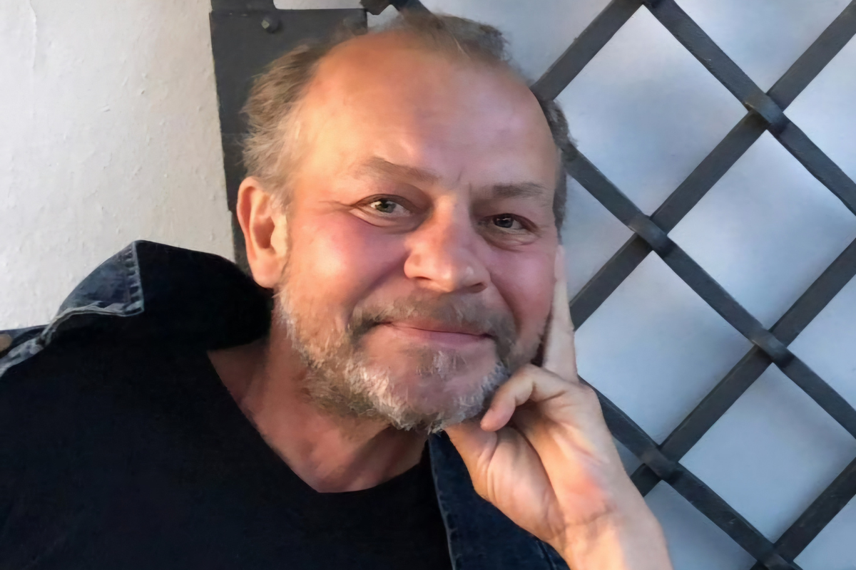 Wojciech Szelachowski uśmiechnięty siwa broda ręką podpiera podbródek