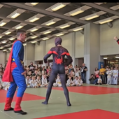 Osby przebrane za superbohaterów walcza w judo.