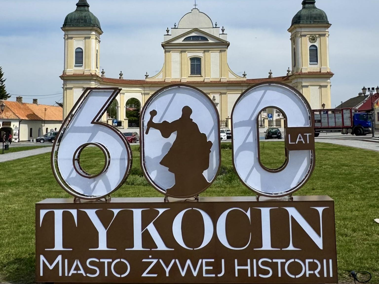 widok na kosciol w tykocinie na pierwszym planie napis tykocin 600 lat miasto zywej historii