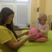 Kobieta trzyma dziecko na stole rehabilitacyjnym.