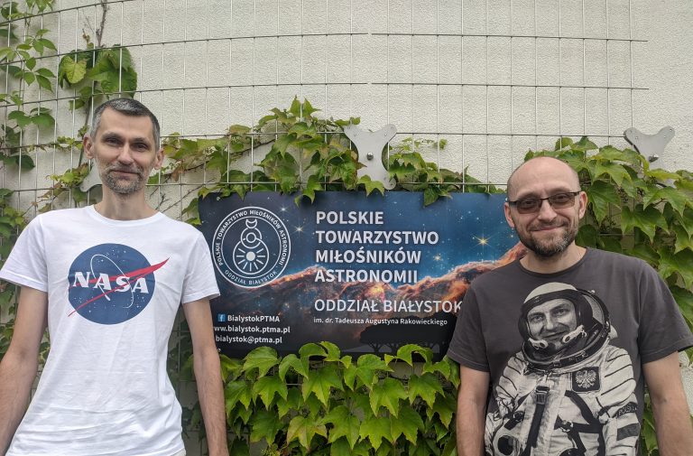 Dwóch mężczyzn stoi przy banerze.