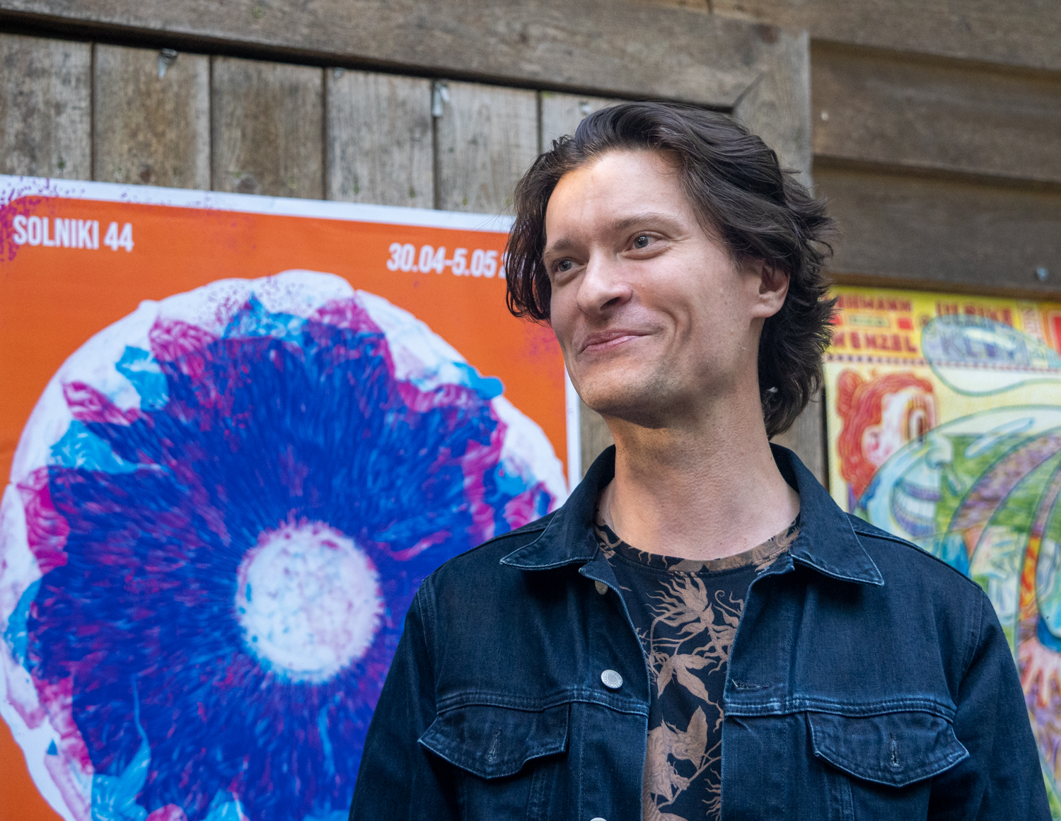 Mężczyzna na tle kolorowego plakatu.