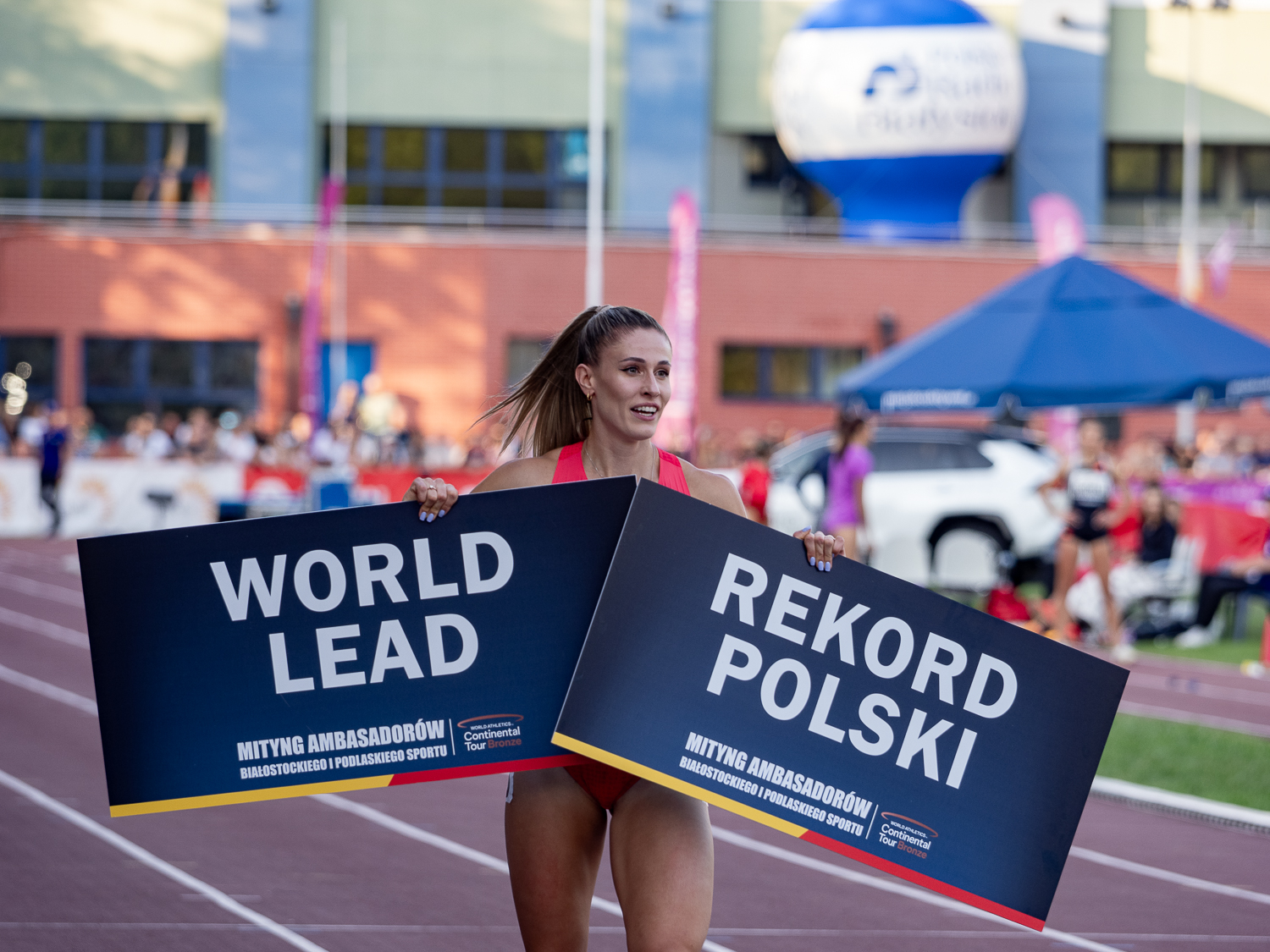 Kobieta na bieżni z plakatami w rękach.