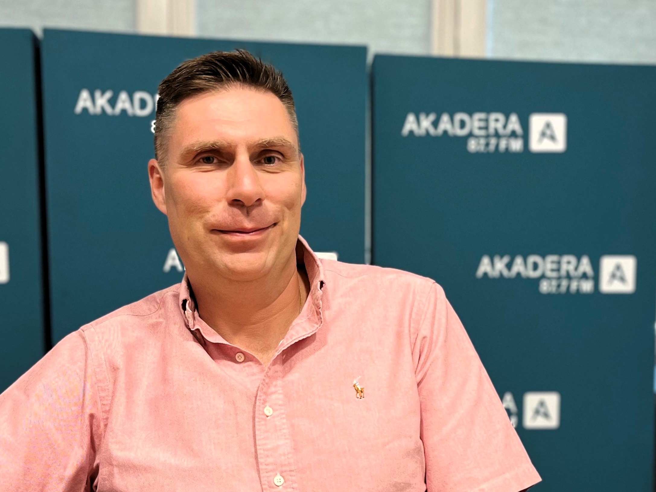 Prof. Adam Hermanowicz w różowej koszuli na tle logo Radia AKADERA 87,7 FM – gość rozmowy o operacyjnym leczeniu otyłości u nastolatków