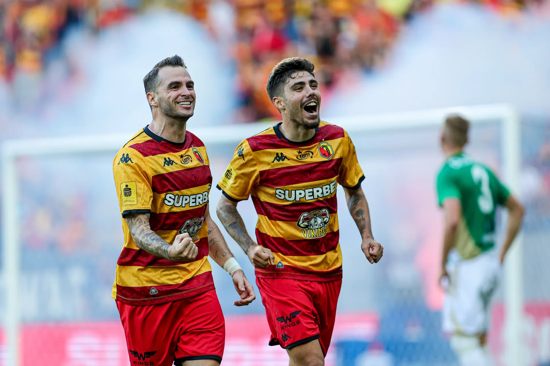 Piłkarze Jagiellonii Białystok cieszą się po strzelonej bramce w meczu z Lechią Gdańsk. Na pierwszym planie Jesus Imaz i Dimitris Rallis w żółto-czerwonych strojach, w tle kibice i boisko.