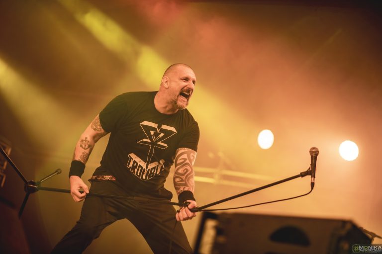 Wokalista zespołu na scenie Summer Dying Loud 2025 w Aleksandrowie Łódzkim – dynamiczny występ w pomarańczowym świetle reflektorów.
