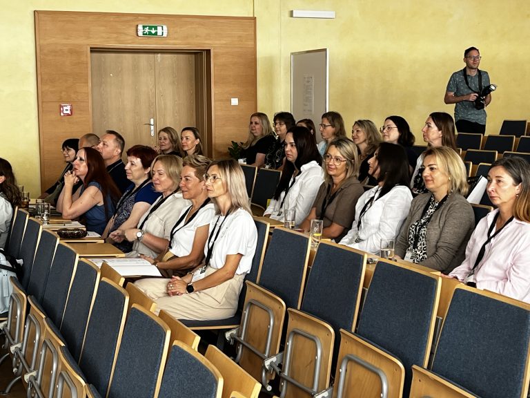Grupa uczestników Sympozjum Pracowników Dziekanatów siedzących w auli Politechniki Białostockiej podczas prelekcji.