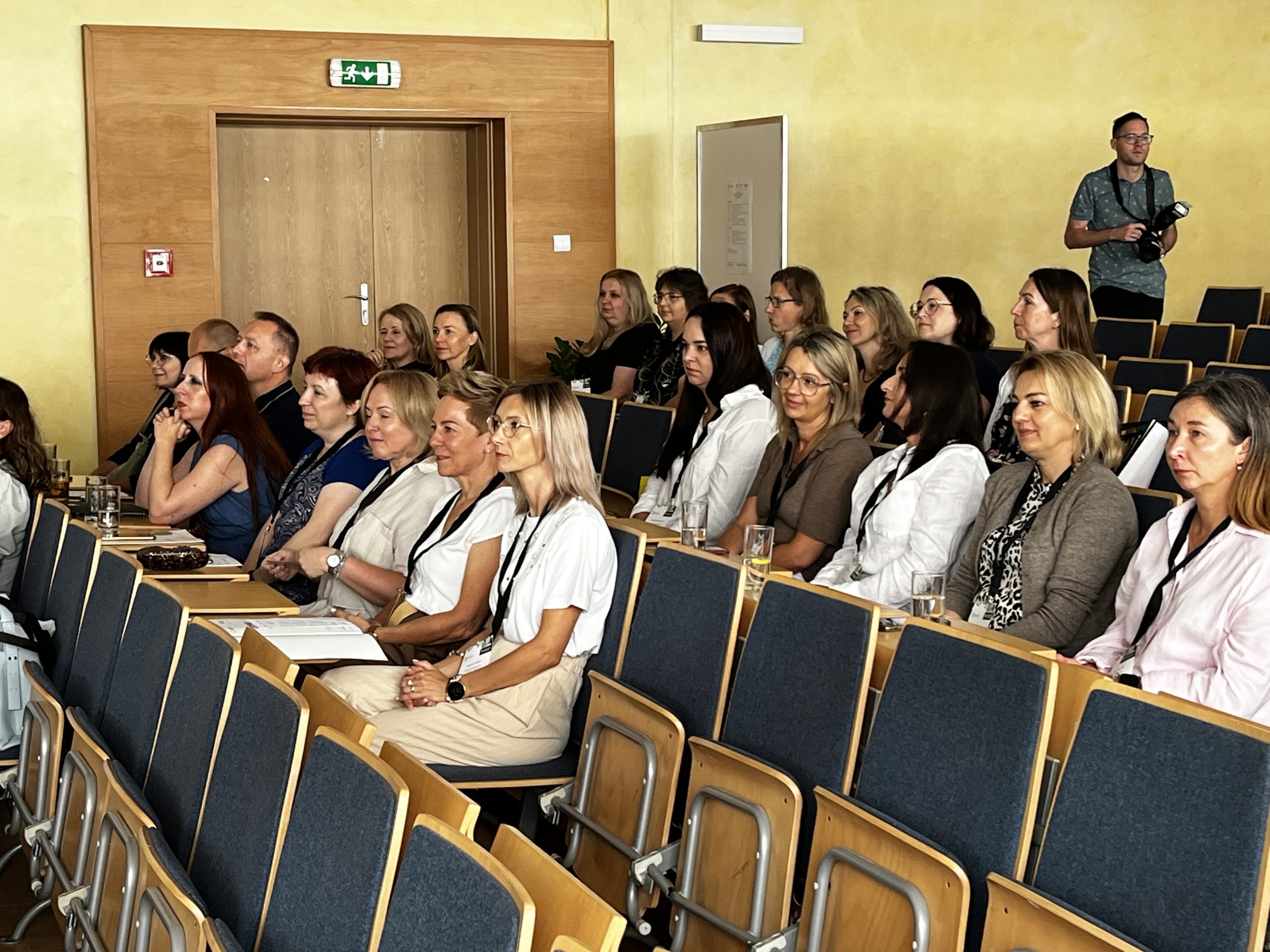 Grupa uczestników Sympozjum Pracowników Dziekanatów siedzących w auli Politechniki Białostockiej podczas prelekcji.