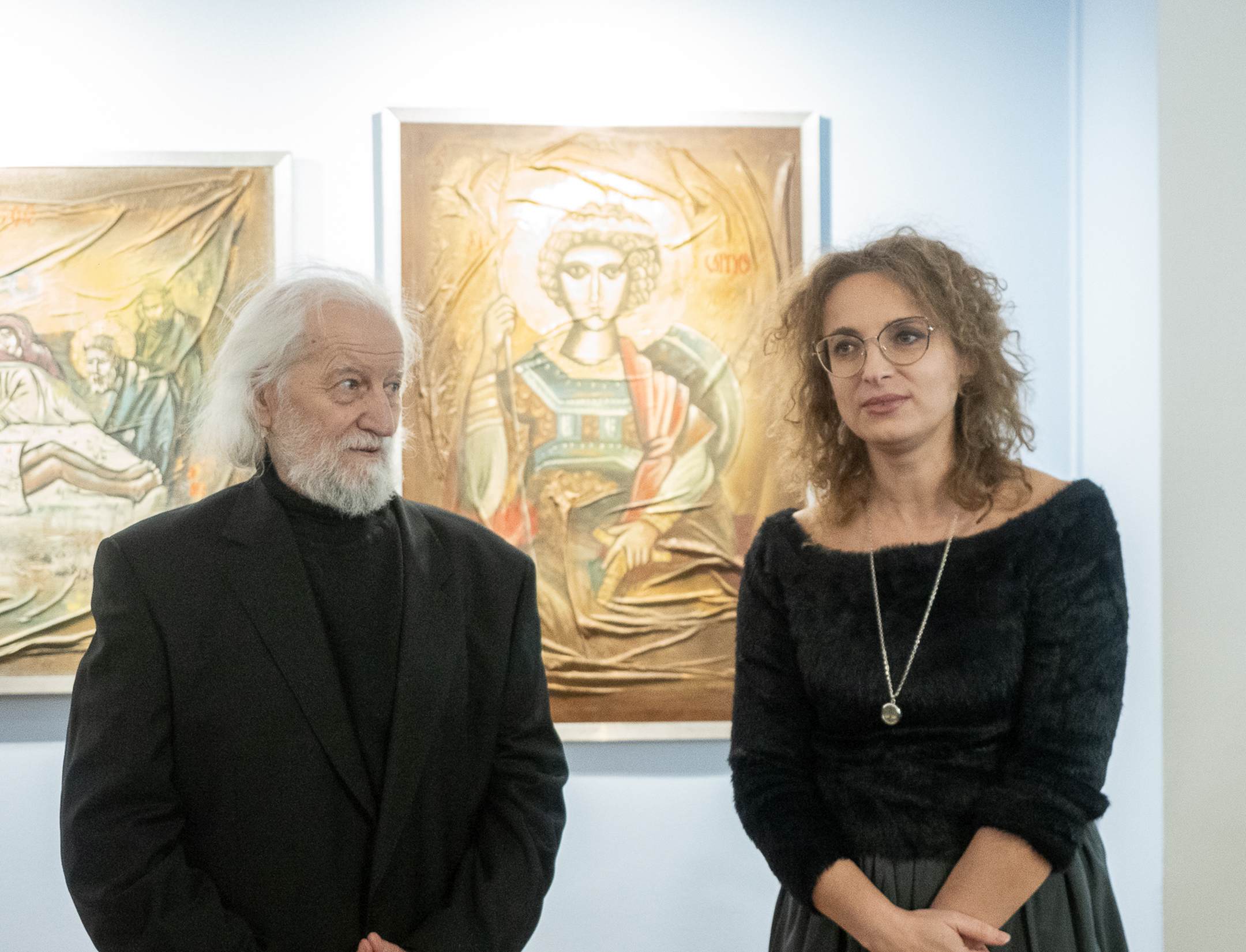 Dymitr Grozdew i kuratorka Marta Pietruszko stoją przed obrazami podczas wernisażu wystawy „Retrospekcja” w Galerii im. Sleńdzińskich w Białymstoku.