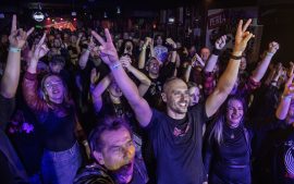 Publiczność w Klubie Sześcian w Białymstoku podczas IX Koncertu Listy Przebojów Kultowej AKADERY, z uniesionymi rękami i entuzjazmem reagująca na występy zespołów rockowych.