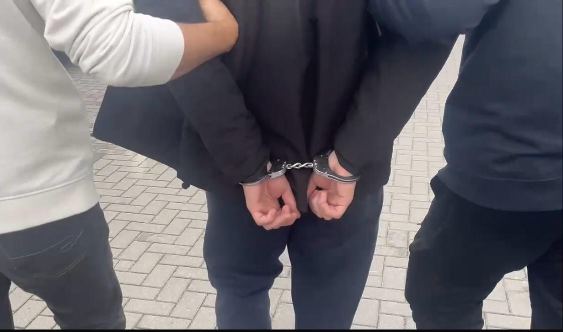 Mężczyzna w kajdankach prowadzony przez policje