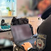 Policjant przy zabezpieczonym laptopie cyberterrorysty