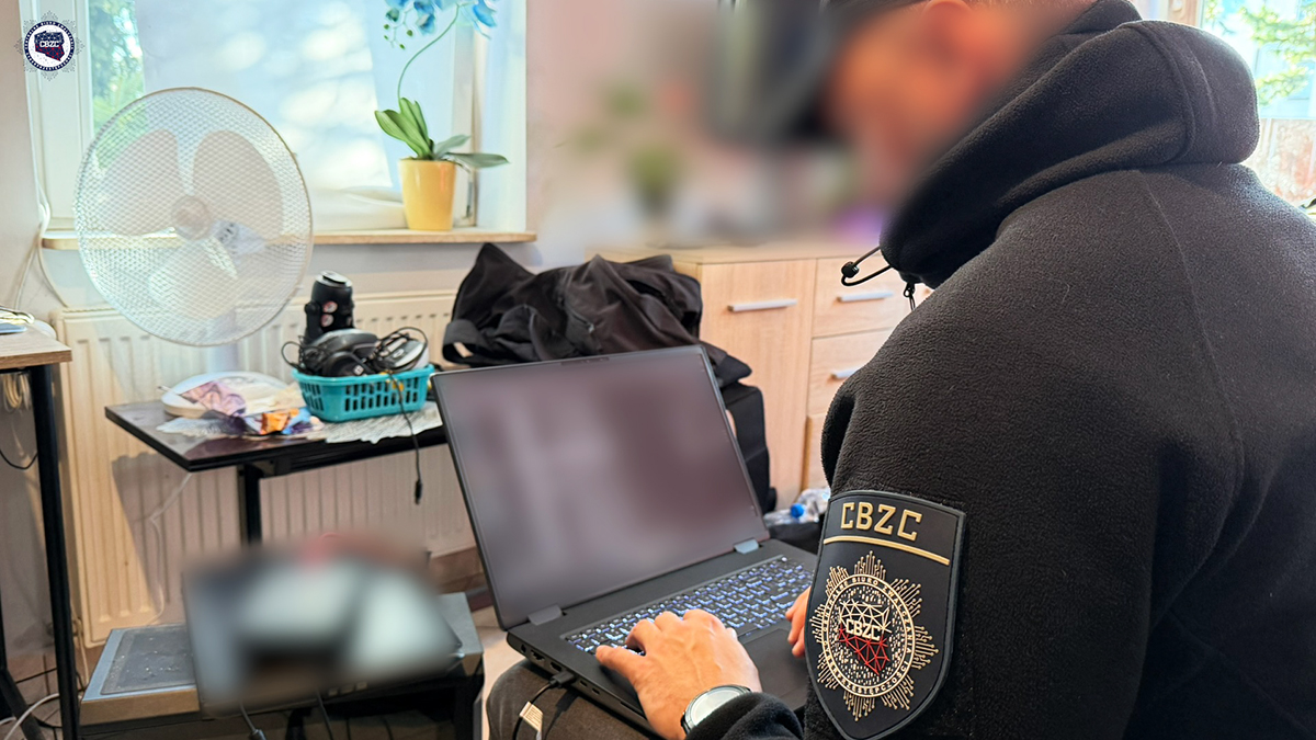 Policjant przy zabezpieczonym laptopie cyberterrorysty
