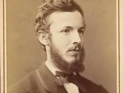 Czarno-biała fotografia młodego Georga Cantora z brodą i w eleganckim garniturze z muszką, patrzącego w bok; portret studyjny z XIX wieku.