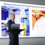 Dr hab. inż. Piotr Mrozek, prof. Politechniki Białostockiej, podczas prezentacji innowacyjnej metody komputerowego projektowania gorsetów ortopedycznych; w tle slajd pokazujący proces wytwarzania gorsetów i przykład ich zastosowania.